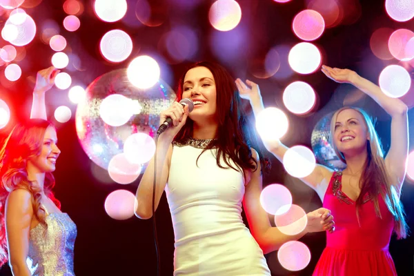 Drei lächelnde Frauen tanzen und singen Karaoke — Stockfoto