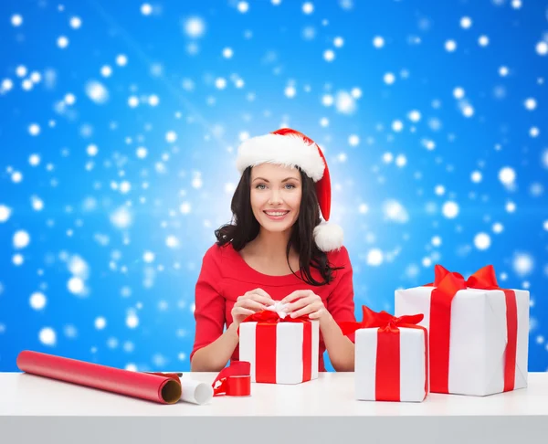 Lachende vrouw in helper KERSTMUTS verpakking geschenken — Stockfoto