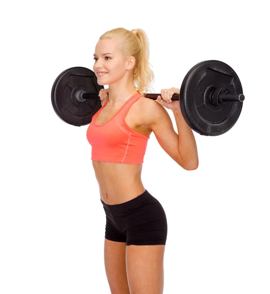 Smiling sporty woman exercising with barbell — Stock Photo, Image