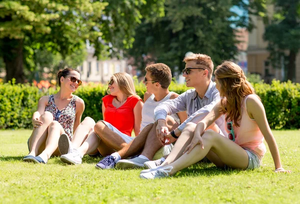 Leende sällskap sitta utomhus på gräs — Stockfoto