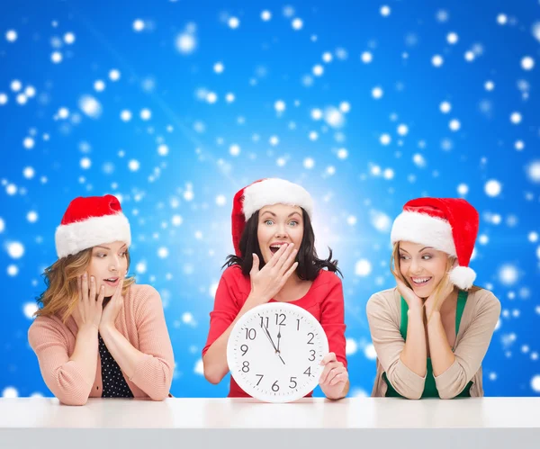 Sonriente mujeres en santa helper sombreros con reloj Imágenes de stock libres de derechos