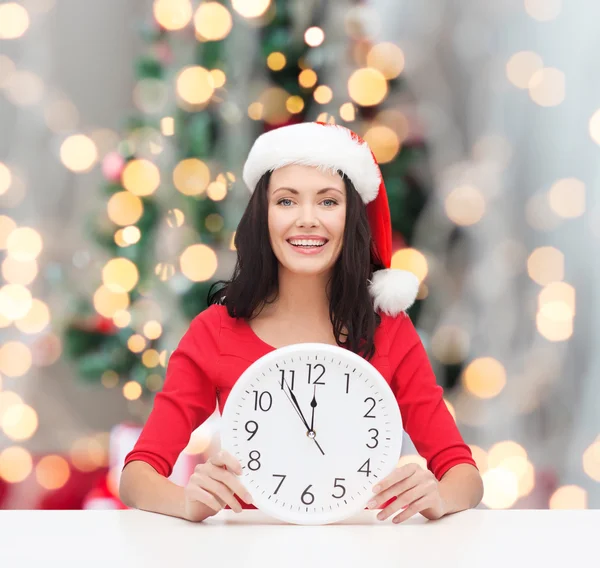 Lachende vrouw in helper kerstmuts met klok — Stockfoto