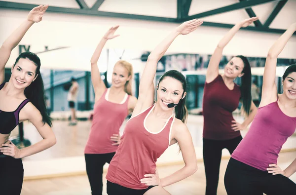 Grupo de personas sonrientes estirándose en el gimnasio —  Fotos de Stock