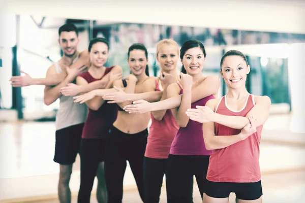 Group of smiling people stretching in the gym Royalty Free Stock Photos