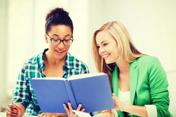 Sorridente studente ragazze lettura libro a scuola — Foto Stock