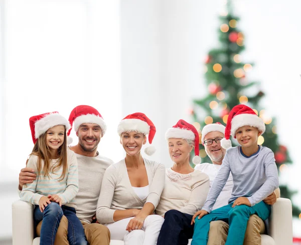 Família feliz em santa helper chapéus sentados no sofá — Fotografia de Stock