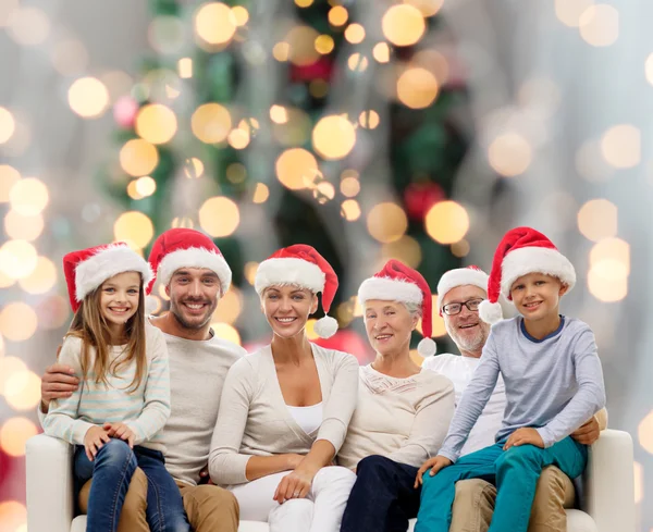 Happy family in santa helper hats sitting on couch — Stock Photo, Image