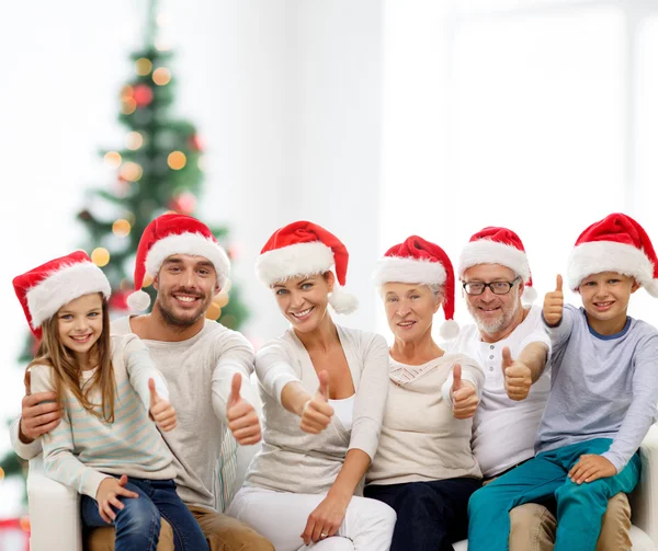 Šťastná rodina v santa klobouky ukazuje palec — Stock fotografie