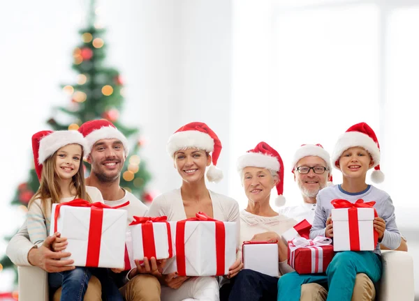 Happy family in santa helper hats with gift boxes — Stock Photo, Image