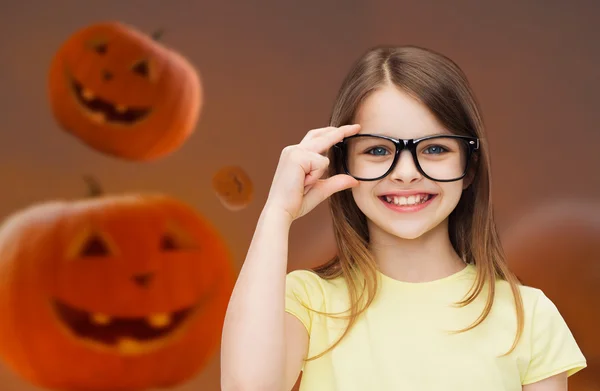 Lachende meisje in glazen over pompoenen achtergrond — Stockfoto