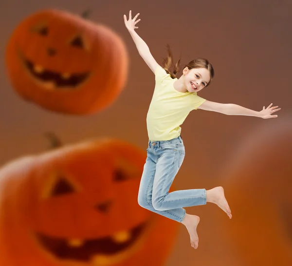 Sonriente chica saltando sobre calabazas fondo — Foto de Stock