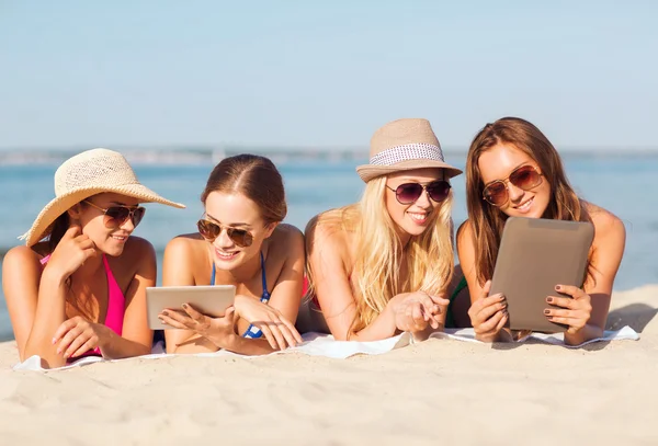 Grupo de mulheres jovens sorridentes com comprimidos na praia — Fotografia de Stock