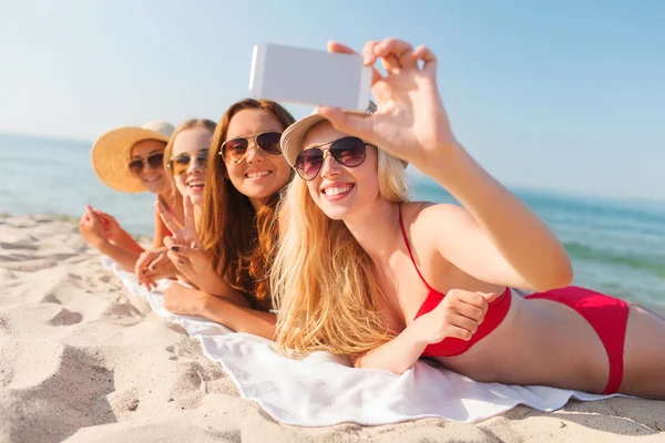 Grupo de mujeres sonrientes con teléfono inteligente en la playa — Foto de Stock