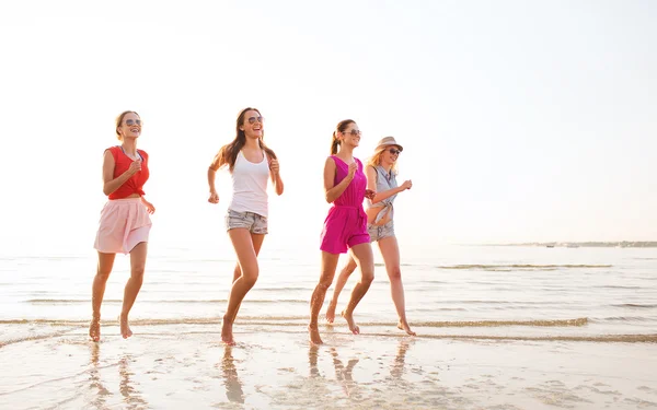 Grupo de mulheres sorridentes correndo na praia — Fotografia de Stock