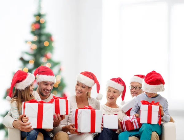 Lycklig familj i santa helper hattar med presentförpackning Stockbild