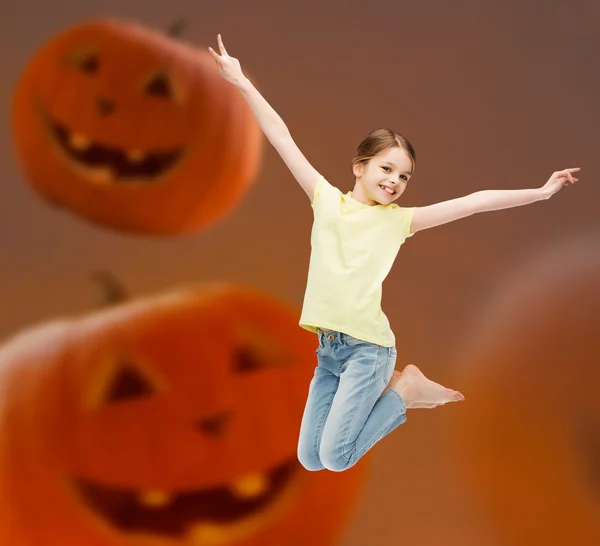 Sonriente chica saltando sobre calabazas fondo — Foto de Stock