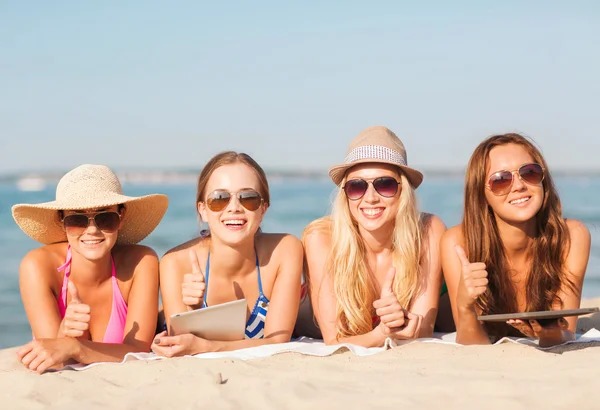 Grupo de mulheres jovens sorridentes com comprimidos na praia — Fotografia de Stock