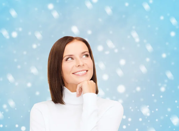 Мыслящая и улыбающаяся женщина в белом свитере — стоковое фото