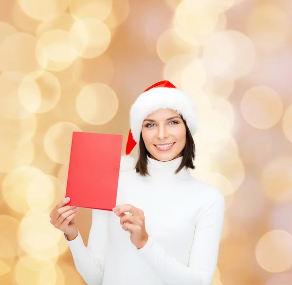 Femme souriante en chapeau de Père Noël avec carte de vœux — Photo