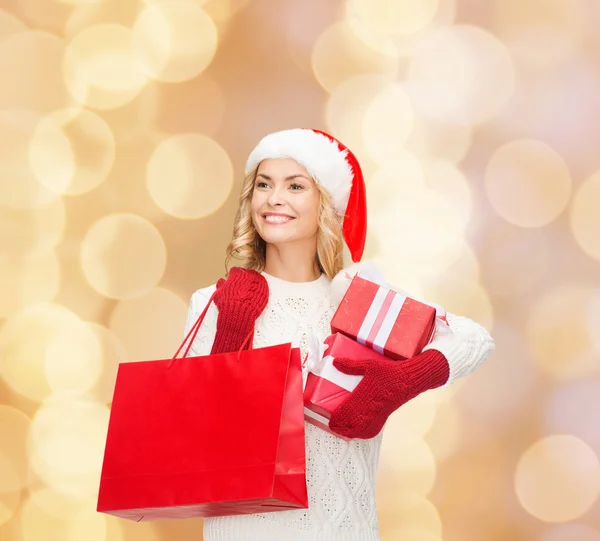 S úsměvem mladá žena v pomocníka čepice santa s dárky — Stock fotografie