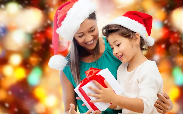 Feliz madre y niña en sombreros de santa con caja de regalo —  Fotos de Stock