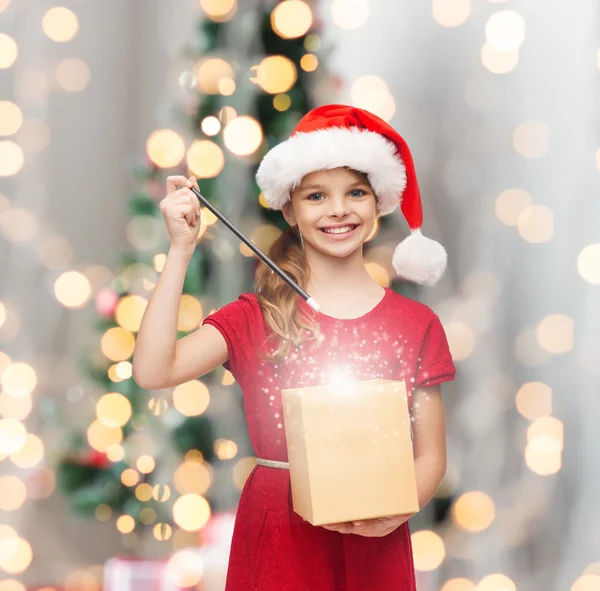 Chica sonriente en sombrero de ayudante de santa con caja de regalo —  Fotos de Stock