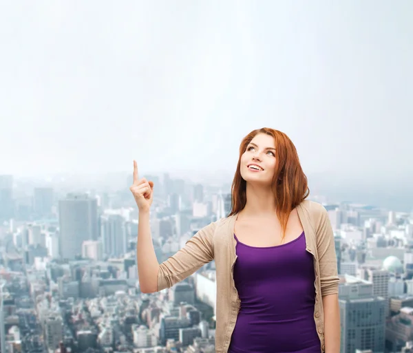 Smiling teenage girl pointing finger up — Stock Photo, Image