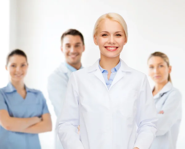 Sorridente médico feminino com grupo de médicos — Fotografia de Stock