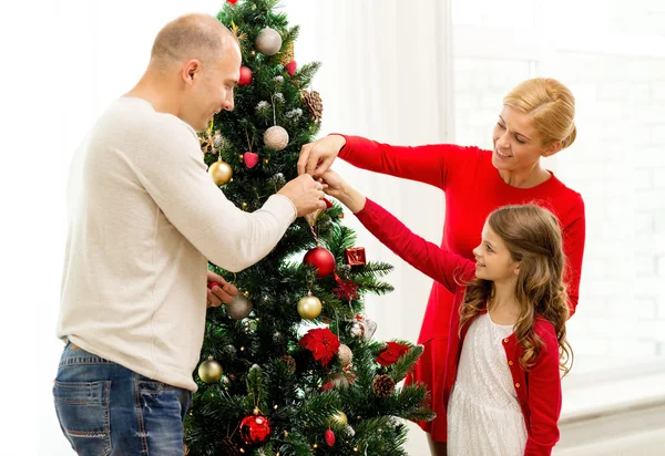 Sonriente familia decorando árbol de Navidad en casa —  Fotos de Stock