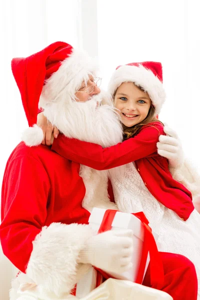 Smiling girl with santa claus and gift at home Royalty Free Stock Photos