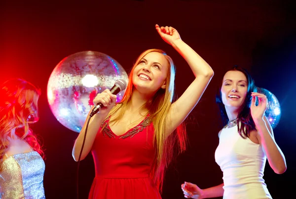 Drie lachende vrouwen dansen en zingen karaoke — Stockfoto