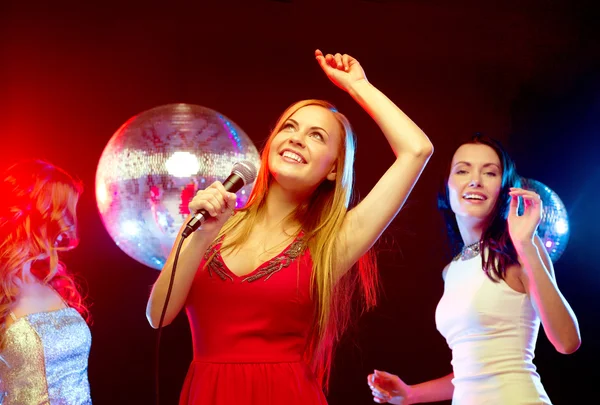 Three smiling women dancing and singing karaoke Royalty Free Stock Images