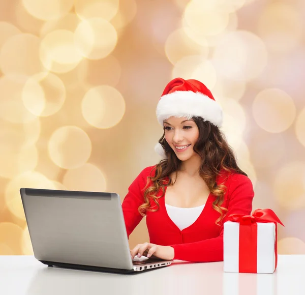 Mulher sorridente com caixa de presente e laptop — Fotografia de Stock