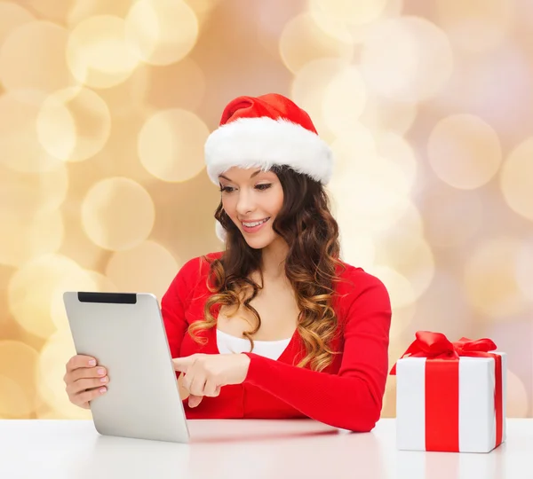 Mujer sonriente en sombrero de santa con regalo y tableta pc — Foto de Stock