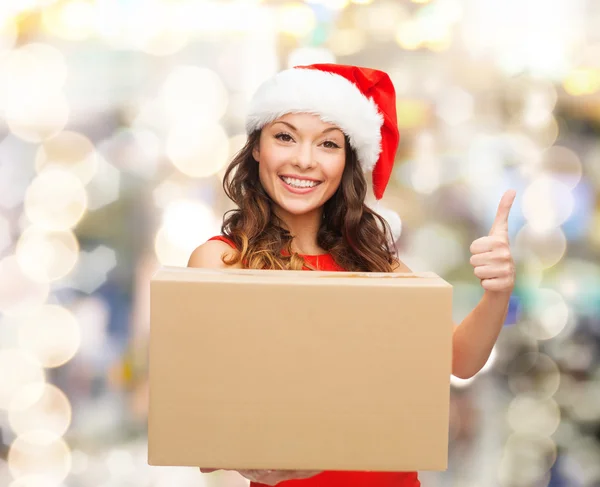 Femme souriante en santa chapeau d'aide avec boîte de colis — Photo