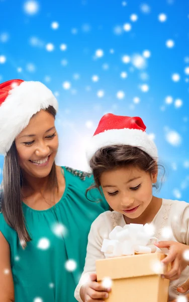 Gelukkig moeder en meisje in santa hoeden met doos van de gift — Stockfoto