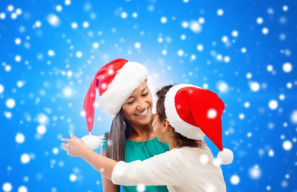 Glad mamma och flicka i santa hattar — Stockfoto