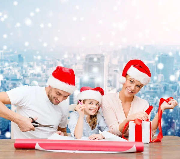 Famiglia felice in cappelli Babbo Natale helper imballaggio regalo — Foto Stock