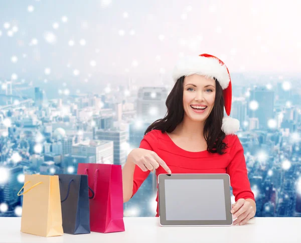 Lachende vrouw in Kerstman hoed met tassen en tablet pc — Stockfoto