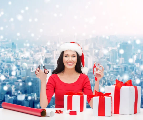 Smiling woman in santa helper hat packing gifts — Stock Photo, Image