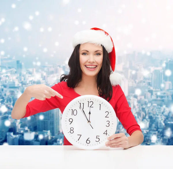 Femme souriante dans santa chapeau d'aide avec horloge — Photo