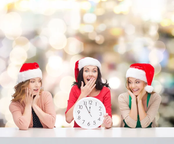 Smiling women in santa helper hats with clock — Stock Photo, Image