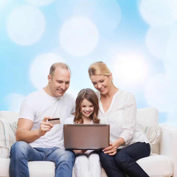 Familia feliz con ordenador portátil y tarjeta de crédito — Foto de Stock