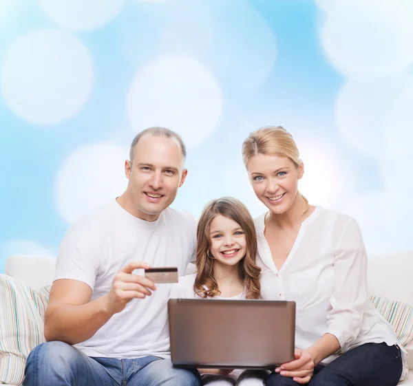 Família feliz com computador portátil e cartão de crédito — Fotografia de Stock
