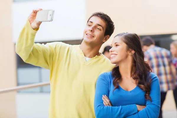 Группа улыбающихся студентов со смартфоном на открытом воздухе — стоковое фото