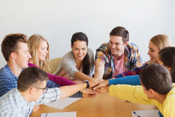 Group of smiling students with hand on top — Stock Photo, Image