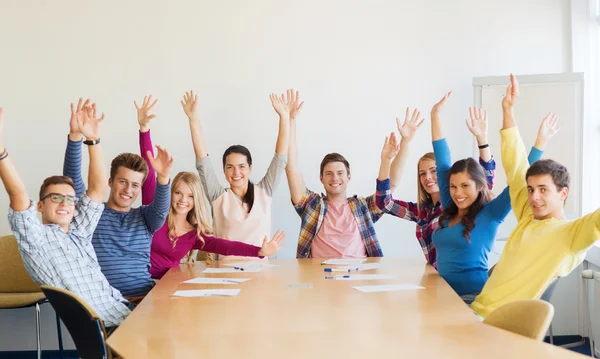 Группа улыбающихся студентов, поднимающих руки в офисе — стоковое фото
