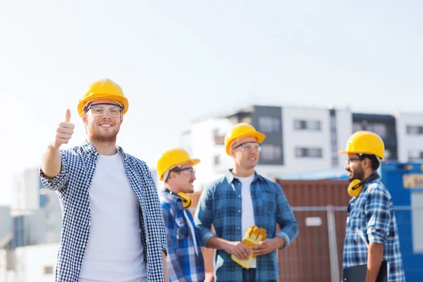 Grupp av leende byggare i hardhats utomhus — Stockfoto