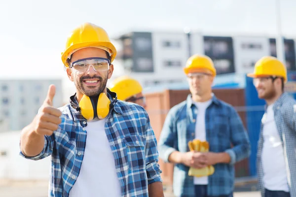 Gruppo di costruttori sorridenti in hardhats all'aperto — Foto Stock