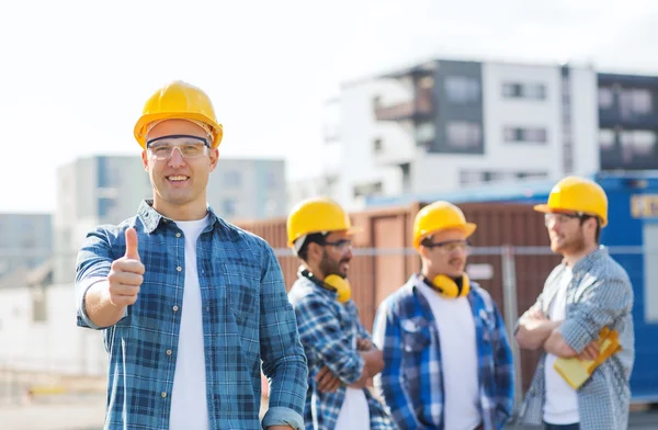 Grupo de constructores sonrientes en hardhats al aire libre — Foto de Stock